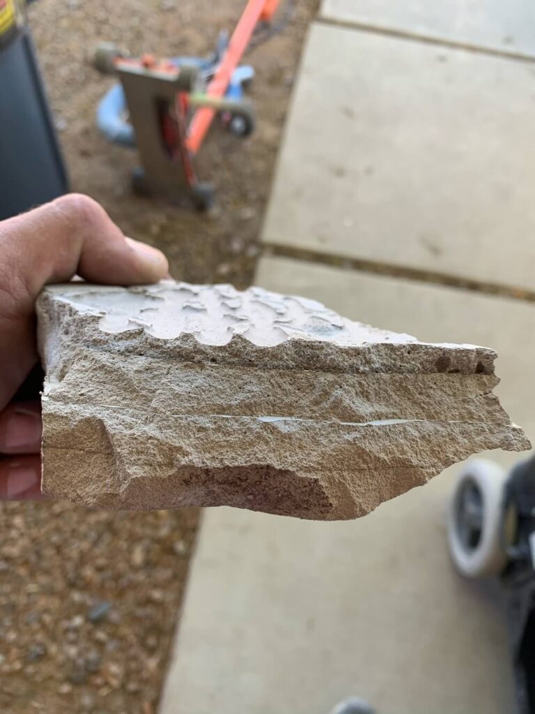 Technician using HEPA-filtered equipment for dustless subfloor preparation before new flooring installation in Phoenix home holds up a piece of subfloor to show how dustless tile removal works